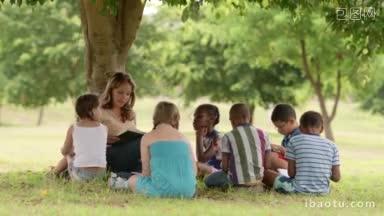 儿童与教育作为教育工作者的年轻妇女在公园里给<strong>男孩</strong>和女孩<strong>读书</strong>